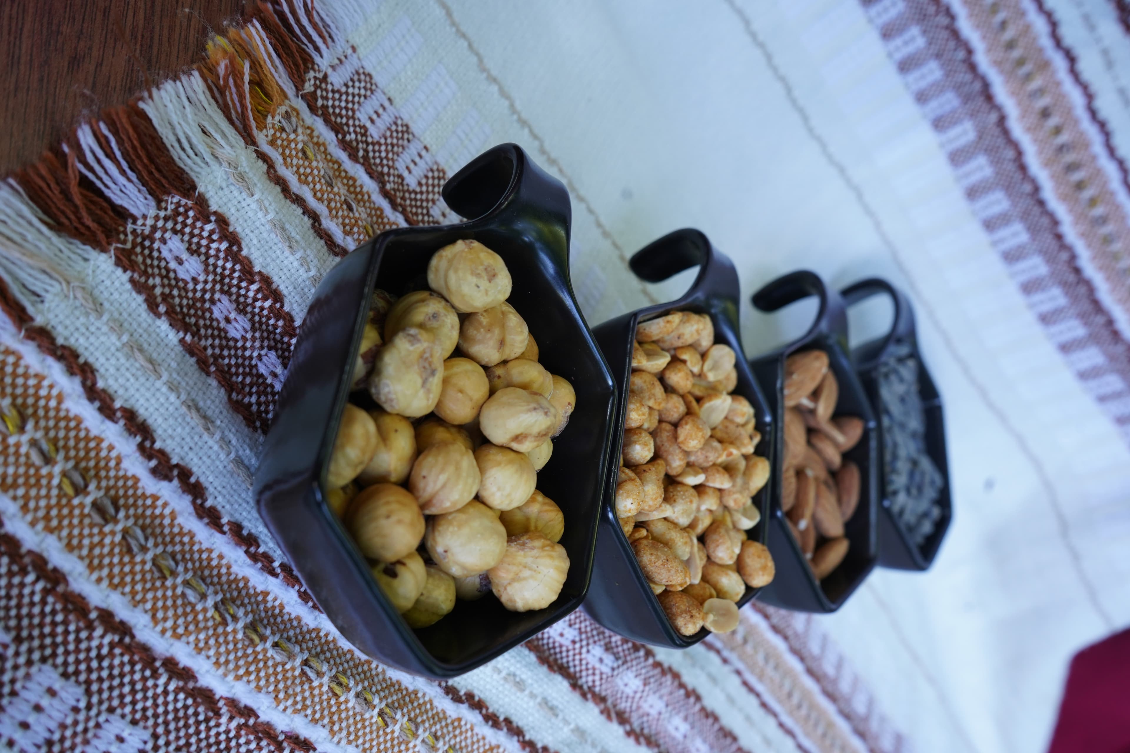 Image of 4 bowls of nuts laid out on a table cloth