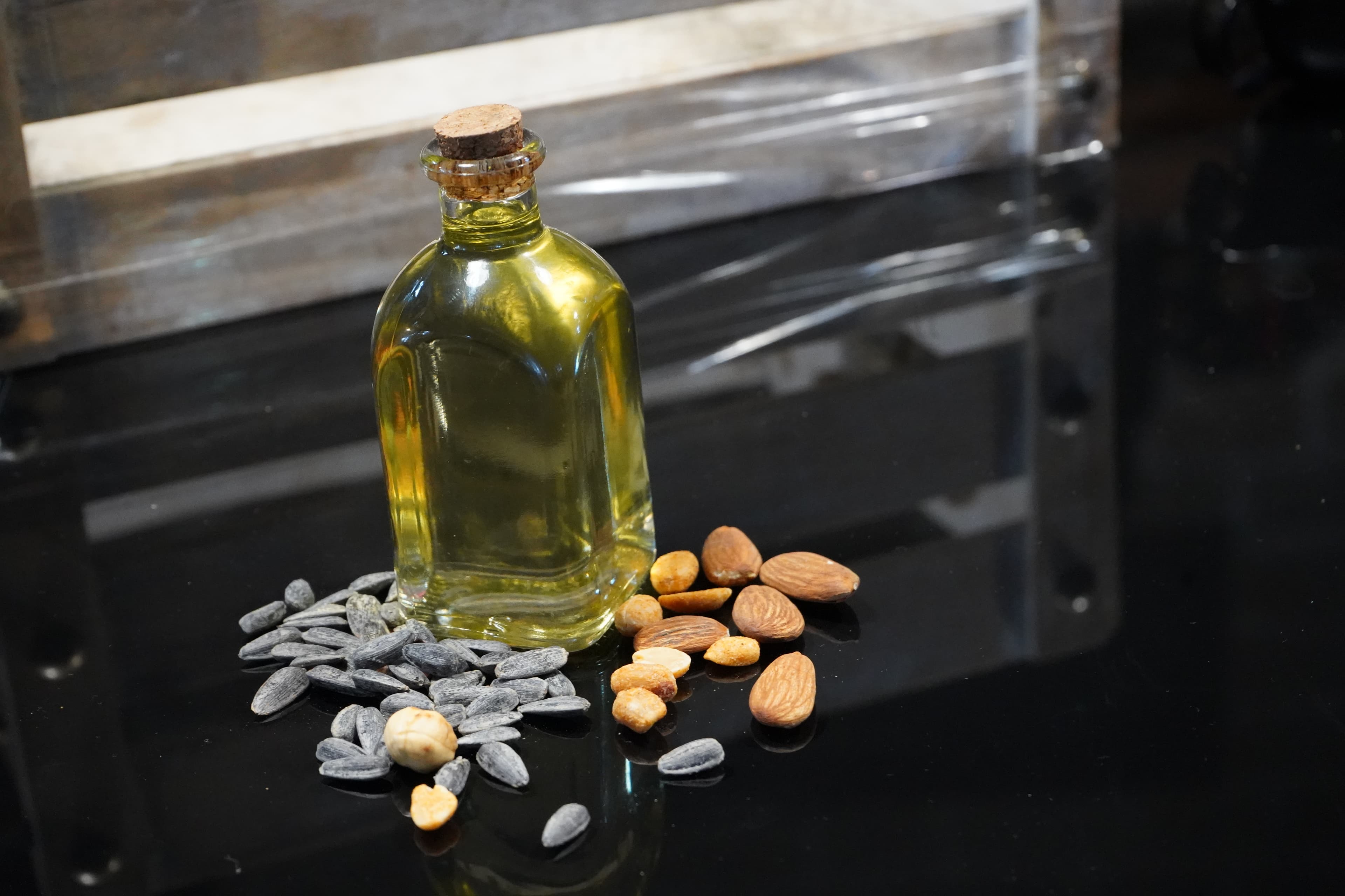 Image of a flask of oil, surrounded by different types of seeds and nuts